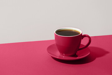 Cup of black coffee on color white and Viva Magenta background for contrast.