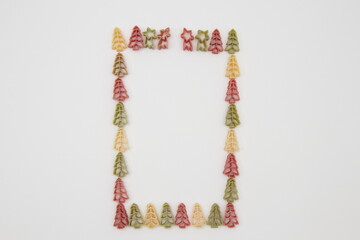 New Year's colorful pasta in the shape of a New Year's tree as a picture frame on a white background with copy space. New year minimalist scene.
