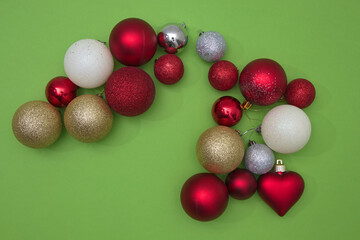 Christmas tree decorations in various colors on a green background with copy space. New Year's scene setting.