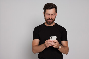 Happy man with smartphone on light background