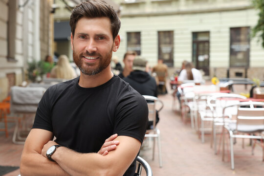 Portrait of handsome bearded man in outdoor cafe, space for text