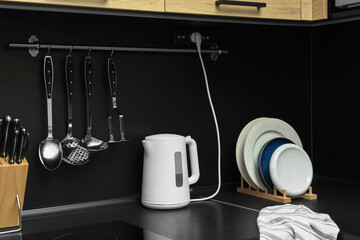 Electric kettle and kitchen utensils on black countertop