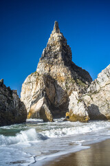 Fototapeta na wymiar Cliffs, sharp spectacular rocks rising from the ocean. waves. Ursa sandy beach under the cliff. Sunny day. Horizontally