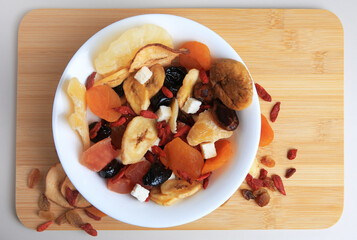 Bowl with different dried fruits on white background, top view