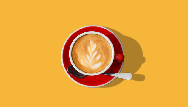 Aromatic coffee in red cup on yellow background, top view