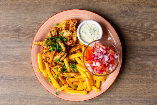French fries, white garlic sauce, vegetable salad bowl on pink plate. Fresh appetizing, yummy, tasty plate of fast food