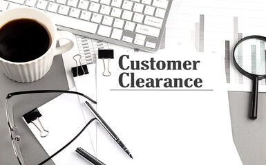 CUSTOMER CLEARANCE text on a paper with magnifier, coffee and keyboard on grey background