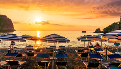 morning or evening landscape with nice beach with deck chairs and umbrellas during sunrise or sunset with amazing sea with rocks and beautiful clouds on background