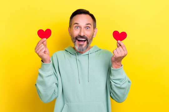 Photo of impressed crazy ecstatic guy dressed mint sweatshirt fingers hold two paper likes staring isolated on yellow color background
