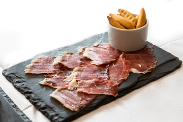 Delicious Iberico or Iberian ham served on a platter with crackers bread