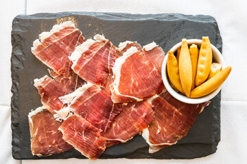 Overhead view of delicious Iberico or Iberian ham served on a platter with crackers bread
