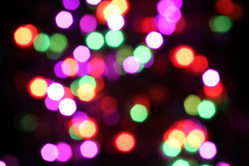Fototapeta premium Blurred yellow, white, red, purple and green lights on black background