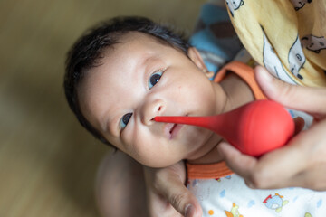 Dad hand sucking mucus from 1 year infant boy noses newborn