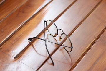 a close up of eyeglasses with black frames isolated natural patterned wooden background.