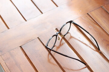 Fototapeta na wymiar a close up of eyeglasses with black frames isolated natural patterned wooden background.