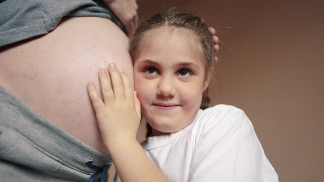 pregnant woman close-up belly. a little girl hugs her mother belly. happy family baby pregnancy newborn concept. daughter listening to baby pregnant mother belly. happy family expecting newborn