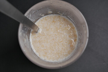 oats, banana and milk in a bowl on black background 
