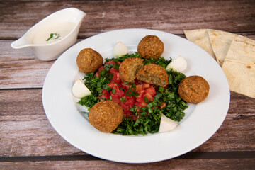 Vegetarian dish, falafel balls from spiced chickpeas with chopped parsley, fresh onions and tomato, tahini sauce, High quality photo