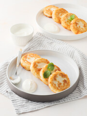 Cottage cheese pancakes, syrniki, on a light background. Copy space.