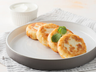 Cottage cheese pancakes, syrniki, on a light background. Copy space.