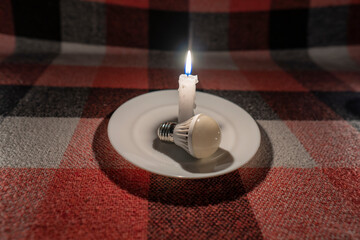 LED light bulb lies near a burning candle