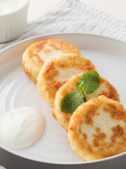 Cottage cheese pancakes, syrniki, on a light background. Copy space.