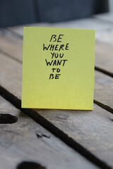 Be where you wont to be. The inscription on the tag on a wooden background.