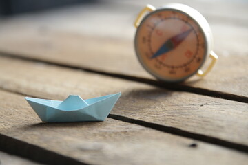 Beautiful paper boat and compass on a vintage background.