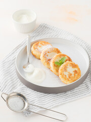 Cottage cheese pancakes, syrniki, on a light background. Copy space.