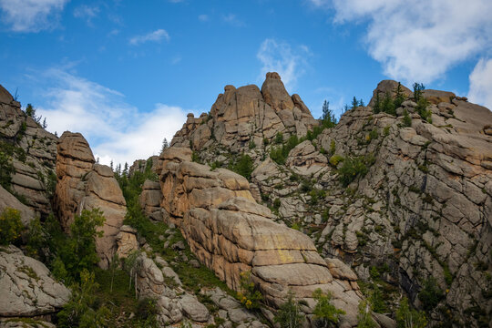 Rocky foothill with the clouds and blue sky in the background. Rock mountain in Mongolia on a cloudy day.