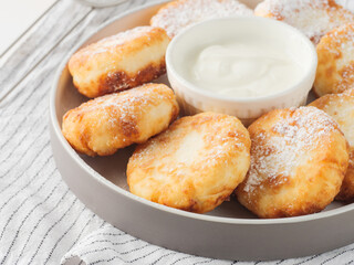 Cottage cheese pancakes, syrniki, on a light background. Copy space.