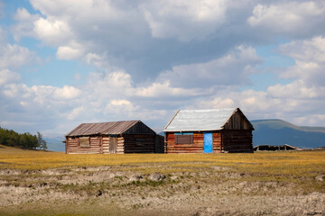 House in the countryside with the mountains in the background. Farm cabin in the rural country surrounded by forest and hills with the snowy tops.