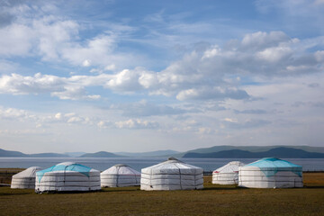 Yurt camp on a beautiful sunny day in Mongolia. Ger campsite in rural country, nature in the background.