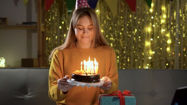 Charming female blowing on candles on birthday cake after making her wish at party at home