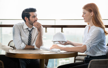 Architect meeting with client explaining construction blueprint for building renovation project. Engineer manager discussion on renovation service agreement deal with customer. Construction industry.