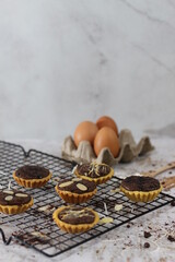 Small chocolate pie with almonds topping served on a cake rack, tastes sweet and savory. Food concept photo.