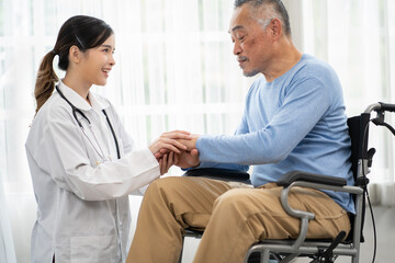 Obraz premium Senior man patient is in wheelchair and young female nurse taking care of him in nursing home. Asian doctor woman supports old man patient to recovery at hospital. Aged people at rehabilitation.