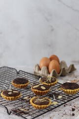 Fototapeta premium Small chocolate pie with almonds topping served on a cake rack, tastes sweet and savory. Food concept photo.