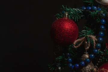 Red Christmas ball on a Christmas tree with a garland on the black background