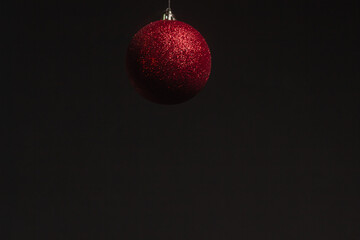 Red Christmas ball on a Christmas tree with a garland on the black background