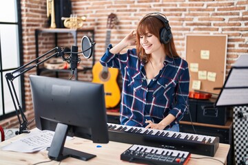 Young woman musician playing piano keyboard at music studio