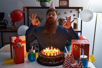 Caucasian man with long beard celebrating birthday holding big chocolate cake relax and smiling with eyes closed doing meditation gesture with fingers. yoga concept.