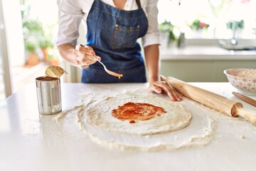 Young blonde woman cooking pizza at kitchen
