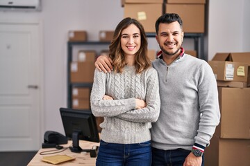 Young hispanic couple working at small business ecommerce looking positive and happy standing and...