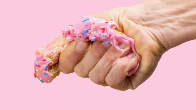 A hand squashing a donut