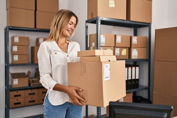 Young hispanic woman ecommerce business worker holding packages at office