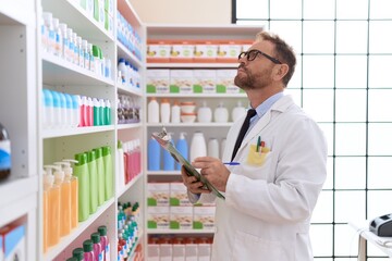 Middle age man pharmacist writing on document at pharmacy