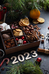 On the table there is a box with nine compartments in which nuts, cookies and spices are poured. On top are the numbers 2023