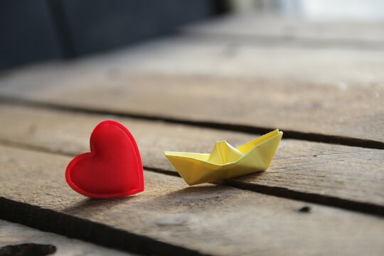 Red heart on a wooden background and paper boat. Place for text. Valentine.