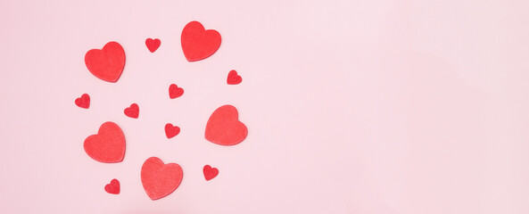 Red wooden hearts on a pink background. The concept of Valentine's day, love, dating and wedding. Symbol of a romantic gift or marriage proposal. Copy space, web banner.